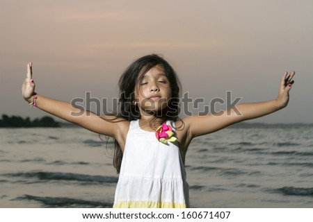 Long black haired girl with her arms outstretched and eyes closed in meditation position