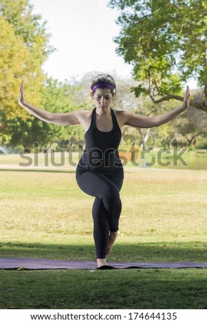 Woman in black sportswear doing a yoga position in a natural park