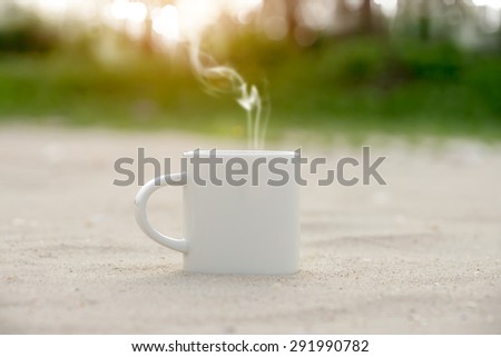 White coffee mug on the beach and sunlight.