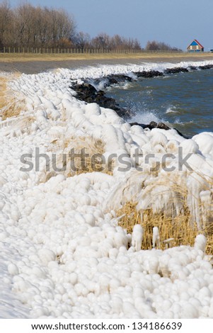 Extreme Ice Storm Hits Lake Shore. Thick ice coats the shore of a dutch lake
