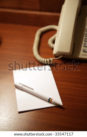 Desk in hotel with a paper and a pen