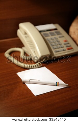 Desk in hotel with a paper and a pen