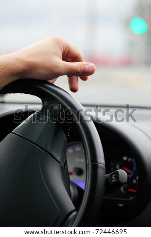 car before a traffic light, a hand of the driver on a steering wheel