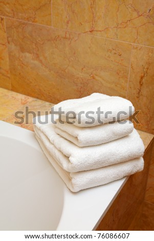 Clean white towels on the brink of a bath