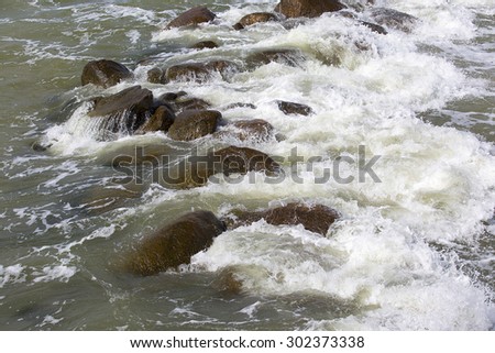 tidal bore: waves with foam and  granite stones