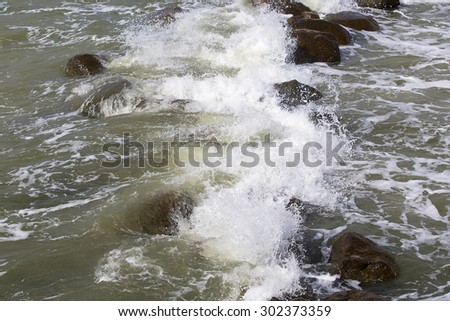 tidal bore: waves with foam and  granite stones