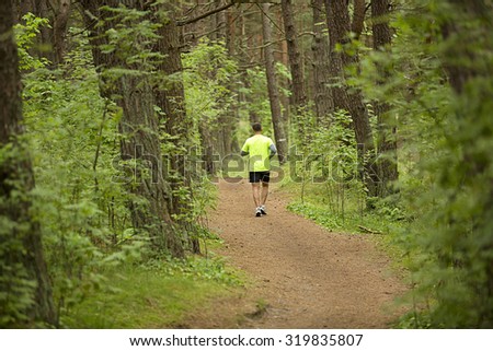 Running man in the forest between the pines