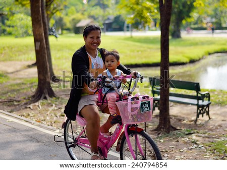 BANGKOK, THAILAND - DEC 29,2014: Unidentified mother and daughter on bicycle at Wachirabenjathus Park or Sorn Rod Fai. This park is called the lungs of Bangkok people.