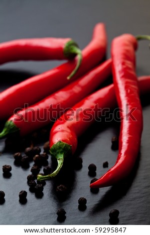 chili peppers with black pepper on dark textured background