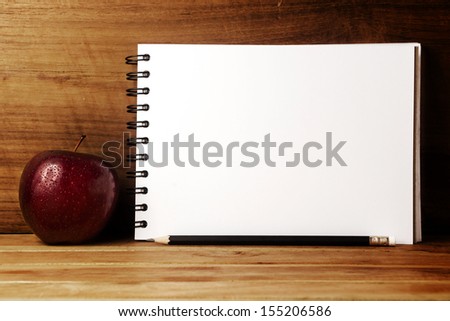 Fresh apple with drops of water,paper and pencil on wood table.
