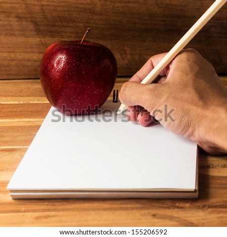 Hand writing and Fresh apple with drops of water on deask
