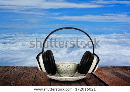 Coffee mug and headphone on wood floor against clear sky background