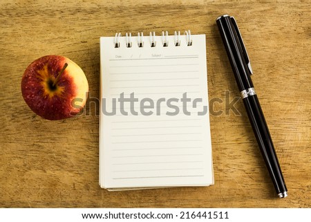 Education and idea concept.Paper sheet,pen and fresh red apple on wood table