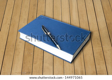 blue hardcover  book with pen  isolated on wood background