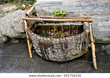 Old Fashioned Chinese Fountain With Engraved Stone Basin and Using Bamboo As Water Conduit.