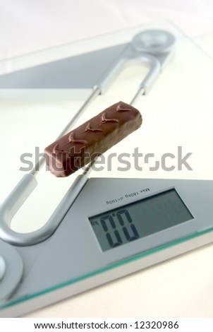 Chocolate bar on the electronic balance showing 0.0kg, methaphore of 