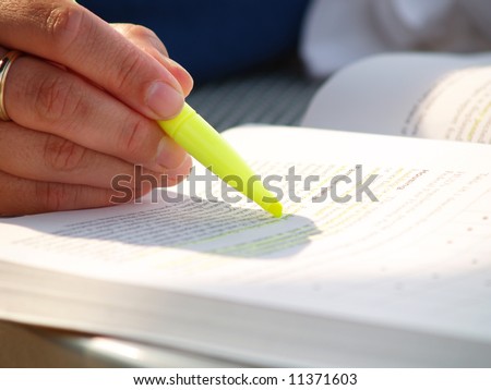 Closeup view of a woman using a highlighter while studying outside in the sunlight