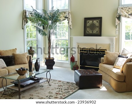 A well decorated family room in a modern american home with an overstuffed sofa, chair and glass coffee table. Large windows make the room very bright and airy.