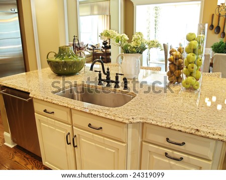 A granite topped island counter in a modern kitchen with dark hardware