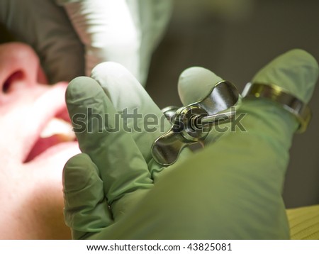 A woman gets an injection at the dentist\'s office before having a root canal. The syringe is in focus, with the patient in the background