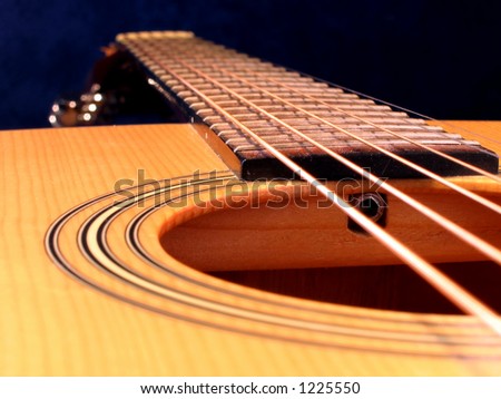 Close up of an acoustic guitar. Strings, frets sound hole and neck.