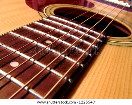 Close up of an acoustic guitar. Strings frets and sound hole.