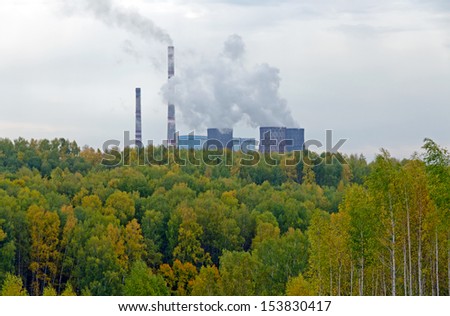 Coal power station behind fall forest