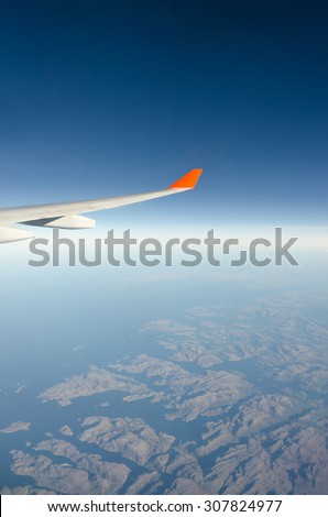 Plane wing, white clouds, blue sky and ground