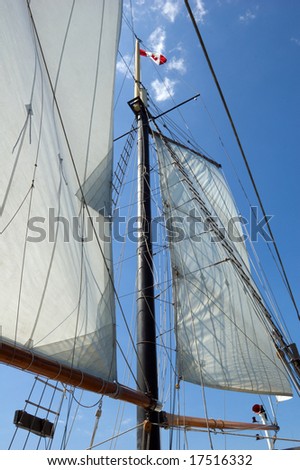 Big sail and Canadian flag on blue sky background