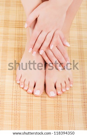 Manicured women\'s hands crossed on his feet