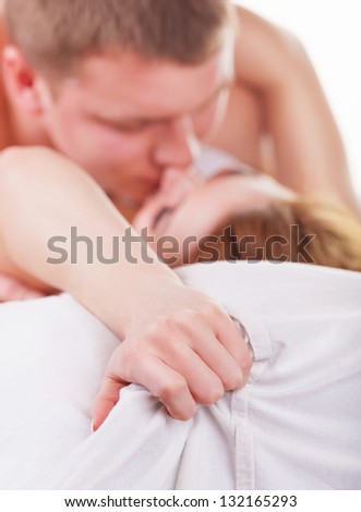 Young beautiful amorous couple making love in bed on dark background