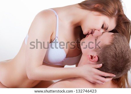 Young beautiful amorous couple making love in bed on white background