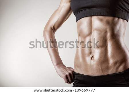 Close-Up Of The Abdominal Muscles Young Athlete On Gray Background