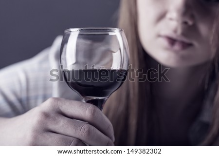 Young beautiful woman in depression, drinking alcohol on dark background
