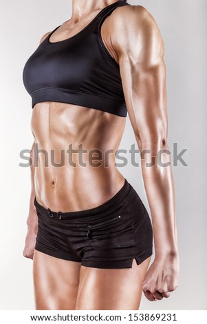 The body of a young athletic girl on gray background - stock photo