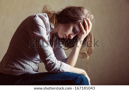 Young sad girl sitting alone in an empty room