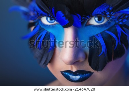 Beautiful woman with make-up with blue feathers