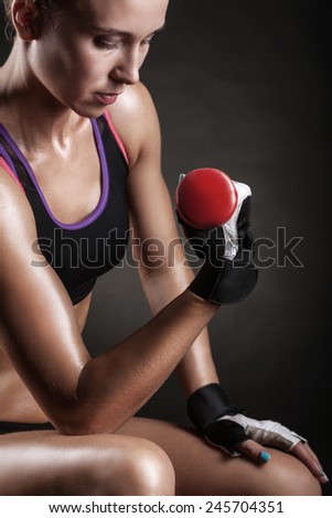 A young woman playing sports with weights on a dark background