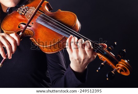 Playing the violin. Musical instrument with performer hands on dark background
