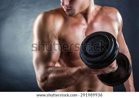 Close Up of a muscular young man lifting weights on dark background
