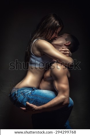 Young sexy couple in each other\'s arms on a dark background