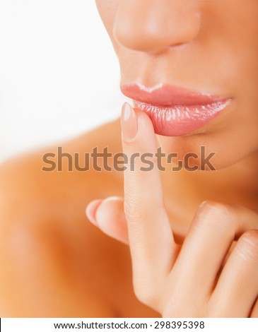 Attractive young woman applying lip balm on a white background