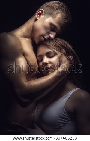 Young beautiful loving couple is embracing on a dark background
