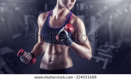 Close-up of a young woman exercising with weights in the gym