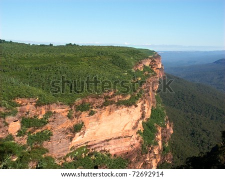 Morning sunlight illuminates a sheer cliff at Blue Mountains National Park of New South Wales, Australia.