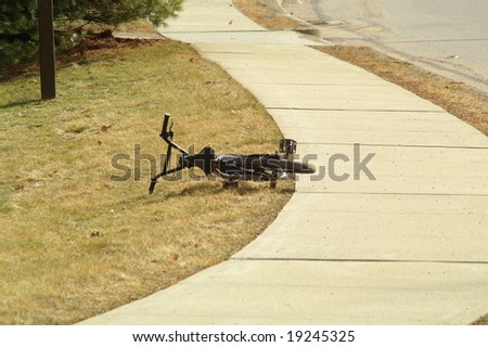 An abandoned bike lies near a sidewalk.