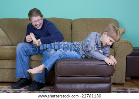 A teenager tickles his younger brother as the brother tries to escape.