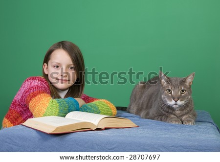A young girl and sits with her cat and a book.