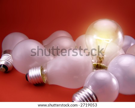 A figurative picture of light bulbs. Dull white lamps (off) with one bright, clear burning bulb. Representing one bright mind/idea in a crowd