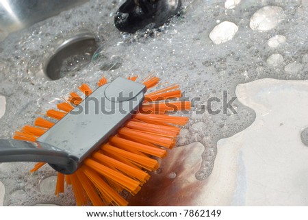 A colorful picture of a orange brush lying in the sink